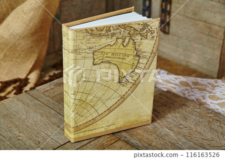 Vintage Map Book Cover on Rustic Wooden Surface with Lace Background 116163526