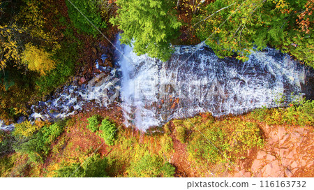 Aerial Top Down Autumn Waterfall in Vibrant Forest Canopy 116163732