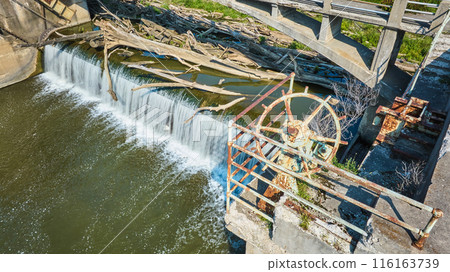 Rusty wheel equipment and railing of Maumee River Dam choked by logs above waterfall Fort Wayne, IN aerial 116163739