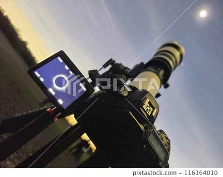 Camera Capturing Solar Eclipse with Telephoto Lens at Twilight 116164010