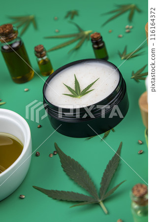 Flat lay composition with hemp oil and hemp leaves on green color background Flat lay composition with hemp oil and hemp leaves on green color background 116164372