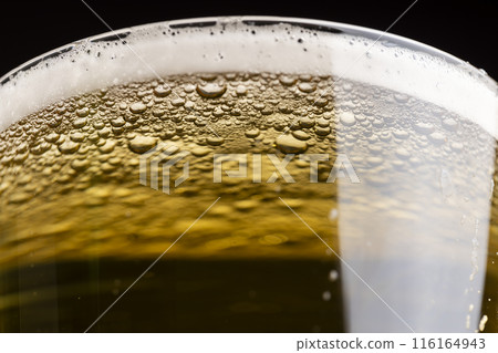 light golden beer in a glass glass on a black background 116164943