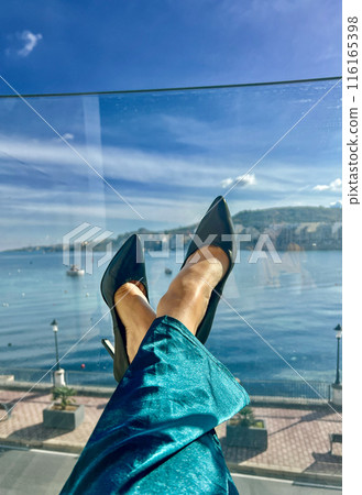 Woman's legs in high heel shoes on the background of the sea. Woman's legs in high heel shoes on the background of the sea. 116165398