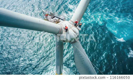 Engineers work on top of wind turbine in sea, aerial view, workers perform maintenance of windmill in ocean at sunset. Concept of energy, power, development 116166050