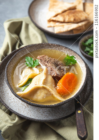 Traditional Jewish Kreplach soup with meat and carrot, gray background Traditional Jewish Kreplach soup with meat and carrot, gray background 116166902