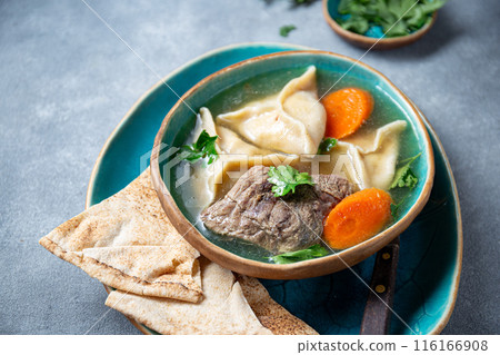 Traditional Jewish Kreplach soup with meat and carrot, gray background Traditional Jewish Kreplach soup with meat and carrot, gray background 116166908