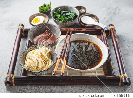 Ingredients for ramen displayed on a light background include ramen noodles, soft-boiled egg, sliced meat, spinach Ingredients for ramen displayed on a light background include ramen noodles, soft-boiled egg, sliced meat, spinach 116166916