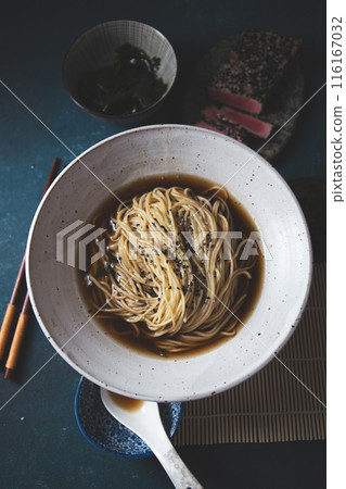 A bowl of ramen featuring perfectly seared tuna slices, garnished with fresh greens, seaweed, and served in a savory broth. A bowl of ramen featuring perfectly seared tuna slices, garnished with fresh greens, seaweed, and served in a savory broth. 116167032