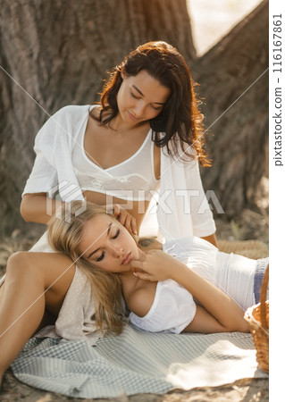Women Relaxing Together On Picnic Blanket In Forest Women Relaxing Together On Picnic Blanket In Forest 116167861