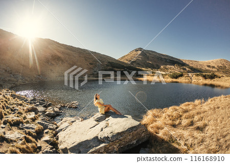 Woman Enjoying Sunlight by Nesamovyte Lake in Carpathian Mountains Woman Enjoying Sunlight by Nesamovyte Lake in Carpathian Mountains 116168910