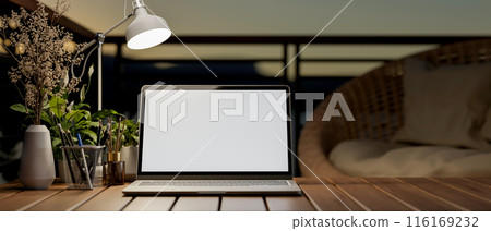 A laptop computer with a white-screen mockup on a wooden table on a balcony. 116169232
