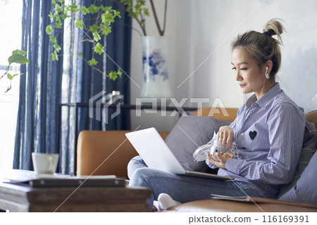 mature asian woman working from home using notebook computer mature asian woman working from home using notebook computer 116169391