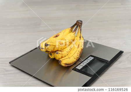 A bunch of ripe bananas on a bathroom scale. 116169526