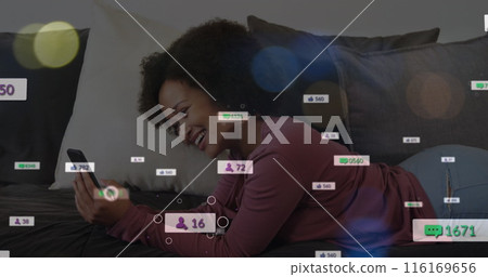 Image of social media icons over african american woman having a imagecall on the couch at home Image of social media icons over african american woman having a imagecall on the couch at home 116169656