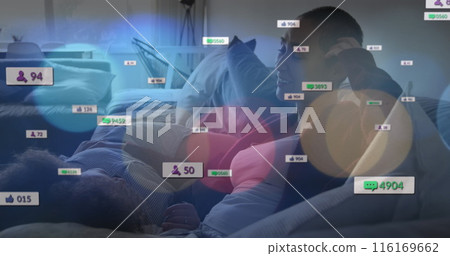 Image of social media icons over diverse lesbian couple mother embracing each other on the couch Image of social media icons over diverse lesbian couple mother embracing each other on the couch 116169662
