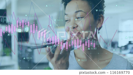 Image of multiple graphs, changing numbers over biracial woman talking on speaker of cellphone 116169770