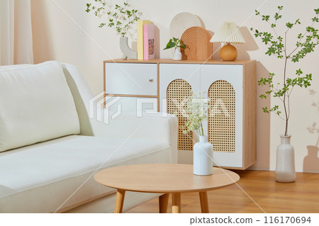 Living room photography with a white sofa placed next to a wooden table contains a flower vase above, in the back is a wooden cabinet with many decorative items on top, empty space for designing Living room photography with a white sofa placed next to a wooden table contains a flower vase above, in the back is a wooden cabinet with many decorative items on top, empty space for designing 116170694