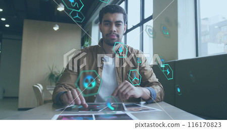 Image of icon in circles over biracial man sitting on chair and looking at camera in office 116170823