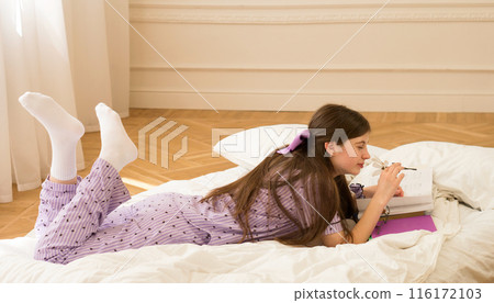 Teen girl reading book on bed Teen girl reading book on bed 116172103