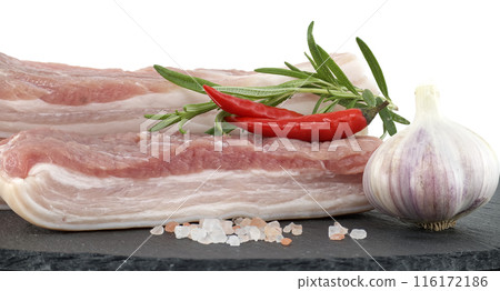 Raw pork belly slices with garlic and chili peppers on a black stone plate 116172186