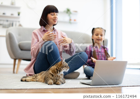 Mother and daughter using laptop with pet cat at home Mother and daughter using laptop with pet cat at home 116172494