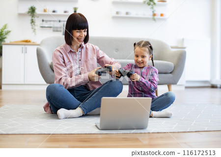 Mother and daughter playing video games together 116172513