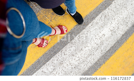 Two pairs of feet on a crosswalk 116172837