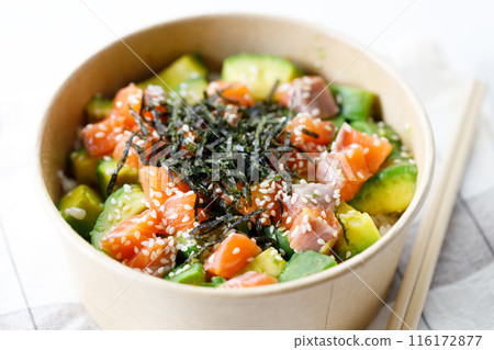 poke bowl with diced raw salmon fish and avocado on sushi rice in paper container. 116172877