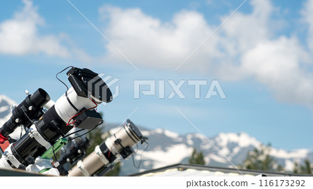Telescopes on observatory rooftop with mountain view. Telescopes on observatory rooftop with mountain view. 116173292