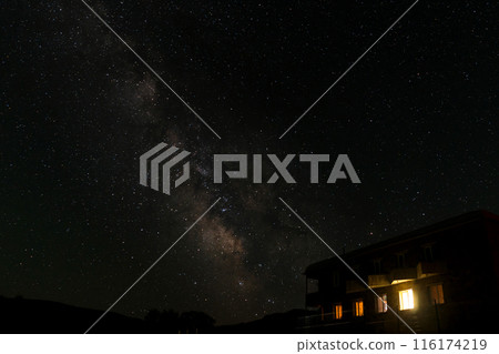 Milky Way galaxy above brightly lit building at night. 116174219