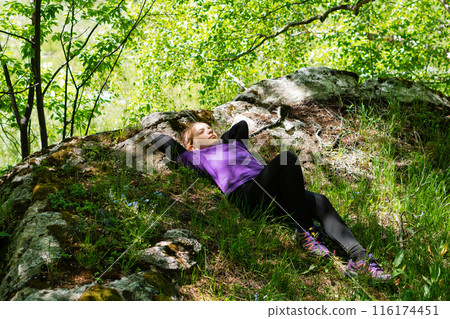 Girl relaxing on rocks in shaded forest area Girl relaxing on rocks in shaded forest area 116174451