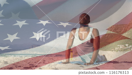 Image of flag of united states of america over african american man practicing yoga on beach 116176313