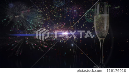 A glass of champagne standing with fireworks bursting in background 116176918
