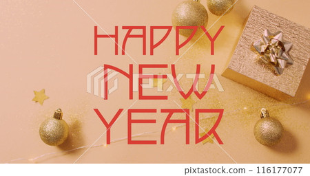 Golden baubles and stars are scattered around gift box on a glittery surface 116177077