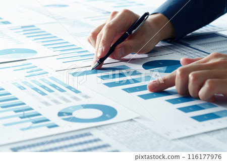 Image of business analysis. A consultant thinking about business strategies. An analyst's hand pointing at a graph among many reports 116177976