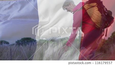 Image of flag of france over happy caucasian woman walking at field 116179557