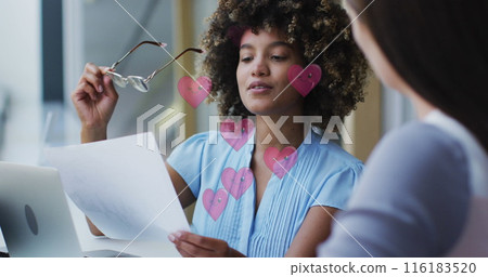 Caucasian colleague holding glasses, discussing with biracial colleague Caucasian colleague holding glasses, discussing with biracial colleague 116183520
