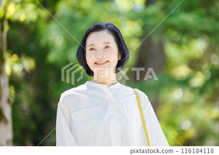 Middle-aged woman walking in the fresh greenery 116184118