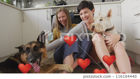 Image of red heart balloon icons over female couple with pet dogs Image of red heart balloon icons over female couple with pet dogs 116184440