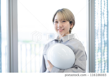 一位身穿工作服、手持頭盔、金髮短髮的年輕女子（自由髮色、以自己的方式工作、工作環境） 116186083