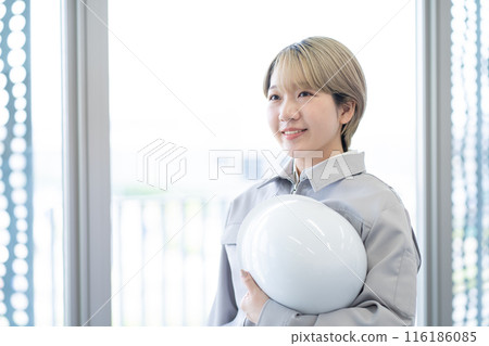 一位身穿工作服、手持頭盔、金髮短髮的年輕女子(自由髮色、以自己的方式工作、工作環境) 一位身穿工作服、手持頭盔、金髮短髮的年輕女子(自由髮色、以自己的方式工作、工作環境) 116186085
