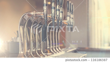 Sunlight highlighting beer taps at bar, showcasing their sleek design 116186387