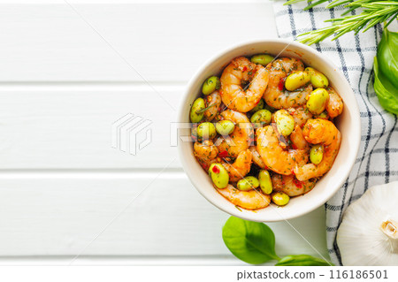 Fresh salad with shrimps and edamame soybeans in bowl on white table. Top view. Fresh salad with shrimps and edamame soybeans in bowl on white table. Top view. 116186501