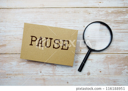 Pause text message and magnifying glass with space copy on wooden background Pause text message and magnifying glass with space copy on wooden background 116188951