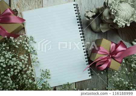 Notebook and gift boxes with pink ribbon and flower decoration on wooden background Notebook and gift boxes with pink ribbon and flower decoration on wooden background 116188999