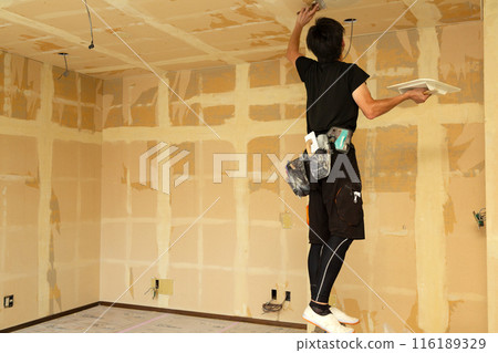 A craftsman replacing wallpaper on a house 116189329