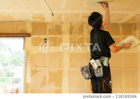A craftsman replacing wallpaper on a house 116189384