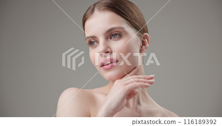 Beauty, health, cosmetics, anti-aging therapy and skin care concept - young beautiful brunette Caucasian woman posing and looking at the camera with a calm confident look like in a mirror Beauty, health, cosmetics, anti-aging therapy and skin care concept - young beautiful brunette Caucasian woman posing and looking at the camera with a calm confident look like in a mirror 116189392