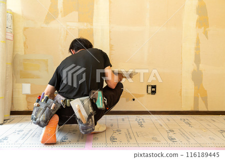 A craftsman replacing wallpaper on a house 116189445