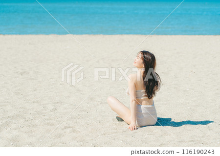 穿著泳衣的年輕女子坐在沙灘上 116190243